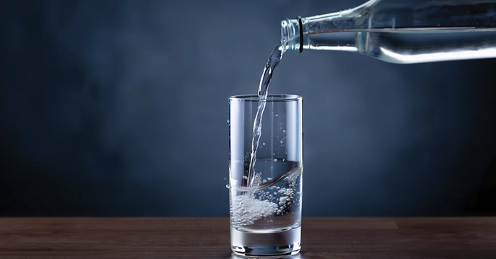 Стакан наполняется минералкой из бутылки